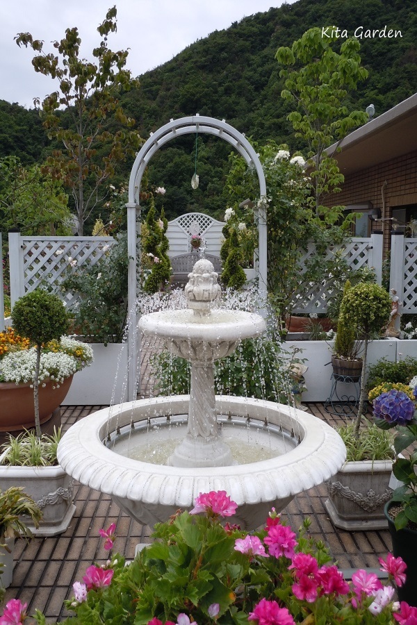 バラのアーチと噴水のある庭